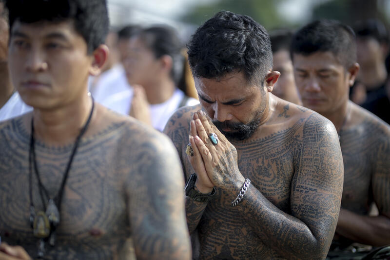 Devotees attend the annual Magic Tattoo Festival at Wat Bang Phra in Nakhon Pathom province, Thailand, 23 March 2024. The Magic Tattoo Festival, also known as the 'Wai Khru Ceremony' (Wai Khru means 'honour the teacher'), attracts devotees from across the country who travel to Wat Bang Phra monastery to receive their traditional tattoos and pay their respects to the temple's master tattooist during the Magic Tattoo Festival. During the festival, devotees sit facing the main shrine before many, 'possessed' by the spirit of the animal tattooed on their skin, stand up, mimic the animal's behaviour and eventually make their way towards the main shrine, sometimes running at high speed, until they are stopped by a group of helpers and medics who bring them out of the trance by rubbing their ears. Receiving a Sak Yant is highly respected in Thailand, and many believe the tattoos have mystical powers to ward off bad luck and protect people from harm. Matrix Images / Diego Azubel