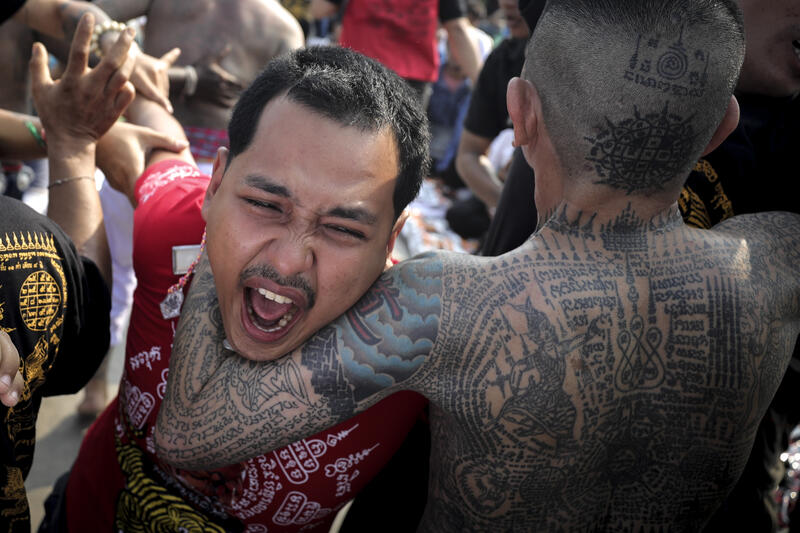 A devotee in a trance, believed to be possessed by the spirits of the animal tattooed on his skin, during the annual Magic Tattoo Festival at Wat Bang Phra in Nakhon Pathom province, Thailand, 23 March 2024. The Magic Tattoo Festival, also known as the 'Wai Khru Ceremony' (Wai Khru means 'honour the teacher'), attracts devotees from across the country who travel to Wat Bang Phra monastery to receive their traditional tattoos and pay their respects to the temple's master tattooist during the Magic Tattoo Festival. During the festival, devotees sit facing the main shrine before many, 'possessed' by the spirit of the animal tattooed on their skin, stand up, mimic the animal's behaviour and eventually make their way towards the main shrine, sometimes running at high speed, until they are stopped by a group of helpers and medics who bring them out of the trance by rubbing their ears. Receiving a Sak Yant is highly respected in Thailand, and many believe the tattoos have mystical powers to ward off bad luck and protect people from harm. Matrix Images / Diego Azubel
