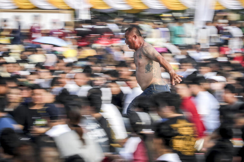 A devotee in a trance, believed to be possessed by the spirits of the animal tattooed on his skin, sprints towards the main shrine during the annual Magic Tattoo Festival at Wat Bang Phra, in Nakhon Pathom province, Thailand, 23 March 2024. The Magic Tattoo Festival, also known as the 'Wai Khru Ceremony' (Wai Khru means 'honour the teacher'), attracts devotees from across the country who travel to Wat Bang Phra monastery to receive their traditional tattoos and pay their respects to the temple's master tattooist during the Magic Tattoo Festival. During the festival, devotees sit facing the main shrine before many, 'possessed' by the spirit of the animal tattooed on their skin, stand up, mimic the animal's behaviour and eventually make their way towards the main shrine, sometimes running at high speed, until they are stopped by a group of helpers and medics who bring them out of the trance by rubbing their ears. Receiving a Sak Yant is highly respected in Thailand, and many believe the tattoos have mystical powers to ward off bad luck and protect people from harm. Matrix Images / Diego Azubel