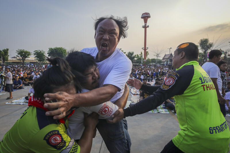 A devotee in a trance, believed to be possessed by the spirits of the animal tattooed on his skin, during the annual Magic Tattoo Festival at Wat Bang Phra in Nakhon Pathom province, Thailand, 23 March 2024. The Magic Tattoo Festival, also known as the 'Wai Khru Ceremony' (Wai Khru means 'honour the teacher'), attracts devotees from across the country who travel to Wat Bang Phra monastery to receive their traditional tattoos and pay their respects to the temple's master tattooist during the Magic Tattoo Festival. During the festival, devotees sit facing the main shrine before many, 'possessed' by the spirit of the animal tattooed on their skin, stand up, mimic the animal's behaviour and eventually make their way towards the main shrine, sometimes running at high speed, until they are stopped by a group of helpers and medics who bring them out of the trance by rubbing their ears. Receiving a Sak Yant is highly respected in Thailand, and many believe the tattoos have mystical powers to ward off bad luck and protect people from harm. Matrix Images / Diego Azubel