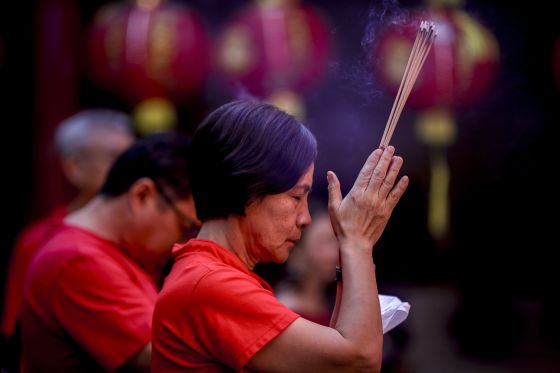 woman prays holding incense
